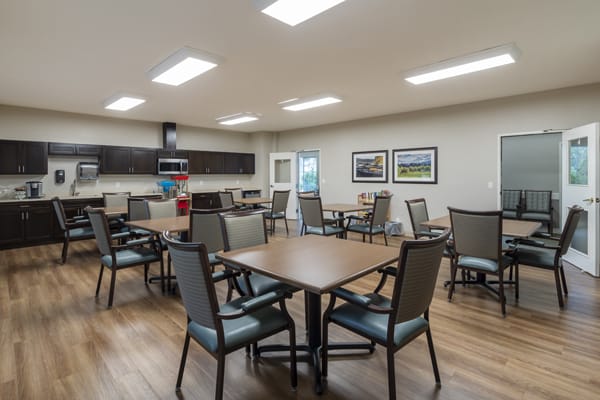 A modern dining area with tables and chairs, well-lit with overhead lights.