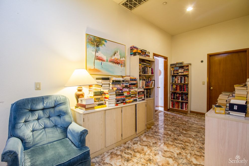 A cozy living space with a comfortable chair, bookshelves filled with books, and a warm lamp lighting the area.