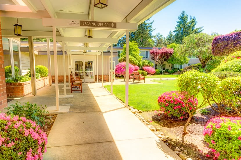A walkway leading to a building surrounded by vibrant gardens on a sunny day.
