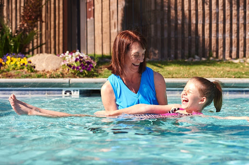 A joyful moment at the pool as a mother helps her child enjoy swimming on a sunny day.