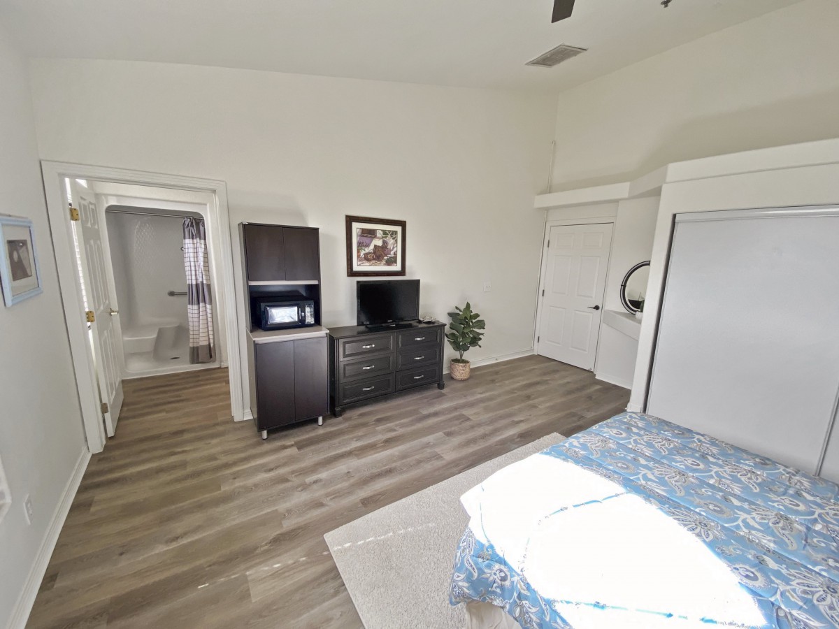 A modern and minimalist bedroom with wooden flooring, featuring essential furniture and decor.