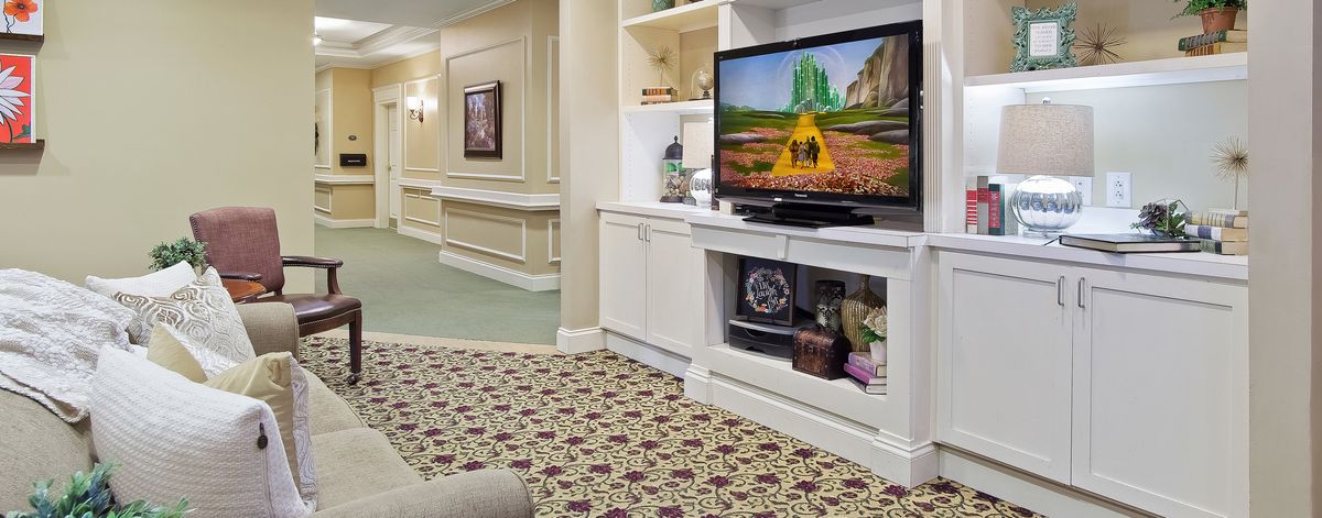 A cozy living room with a television and patterned carpet.
