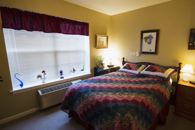 A cozy bedroom with a colorful bedspread and decorative elements.