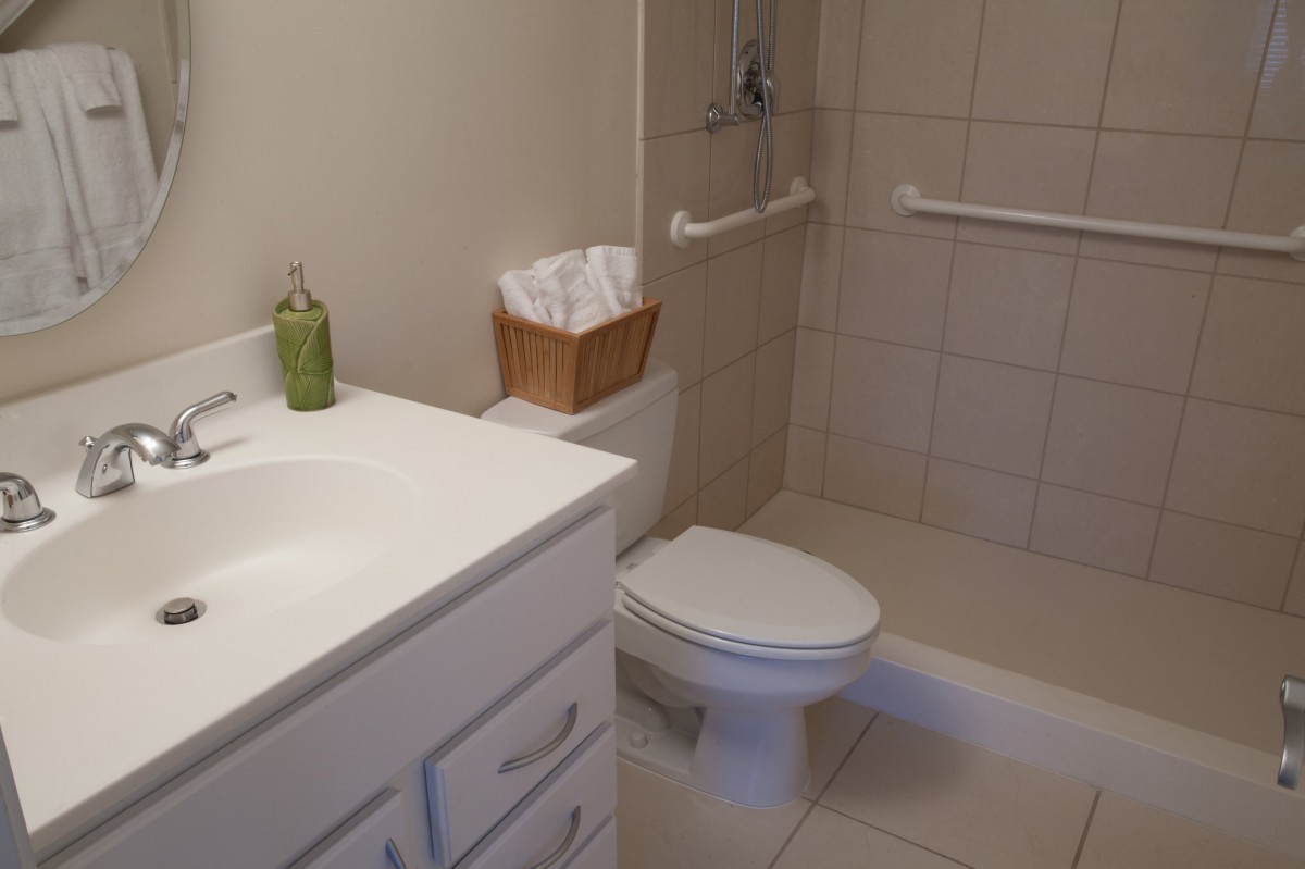 A clean and tidy bathroom with a toilet, sink, and shower area.