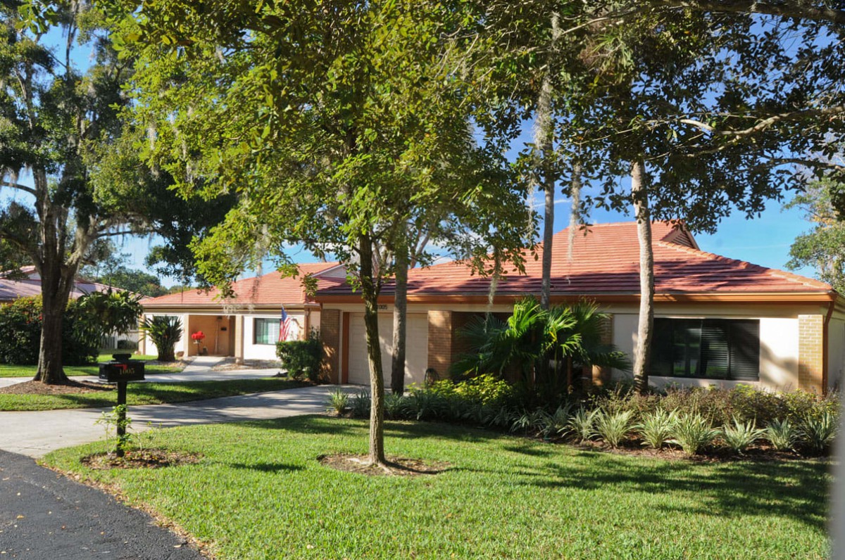 A suburban house with a manicured lawn and mature trees.