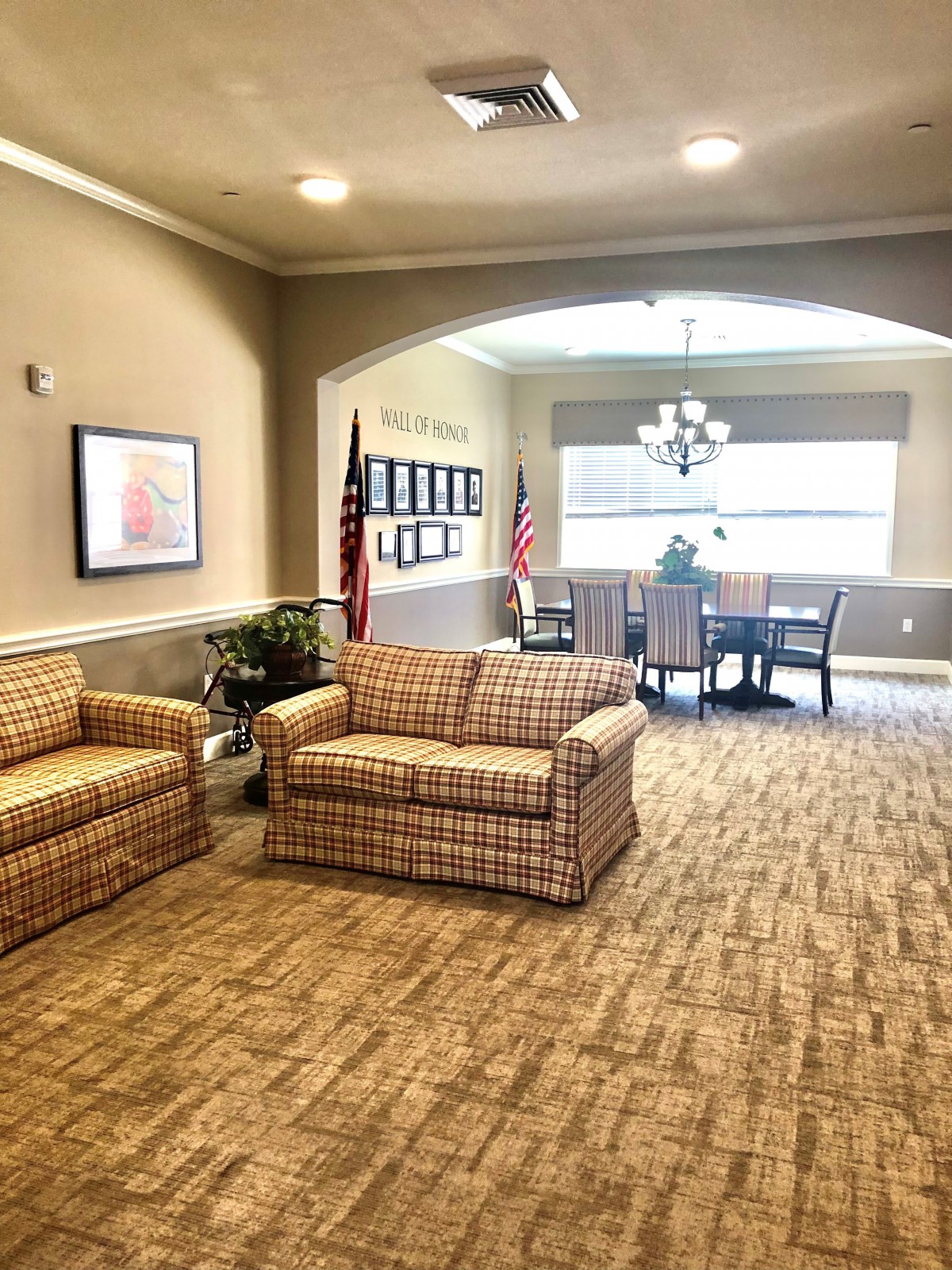 A cozy lobby area with sofas and a table, adorned with flags and soft lighting.