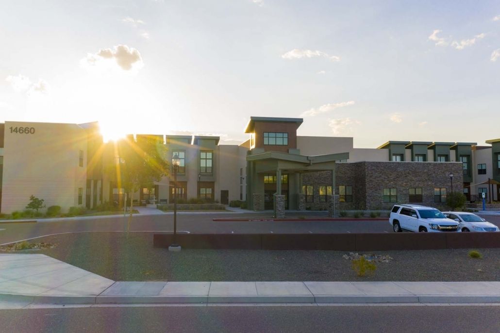 A modern building with a parking area at sunset.