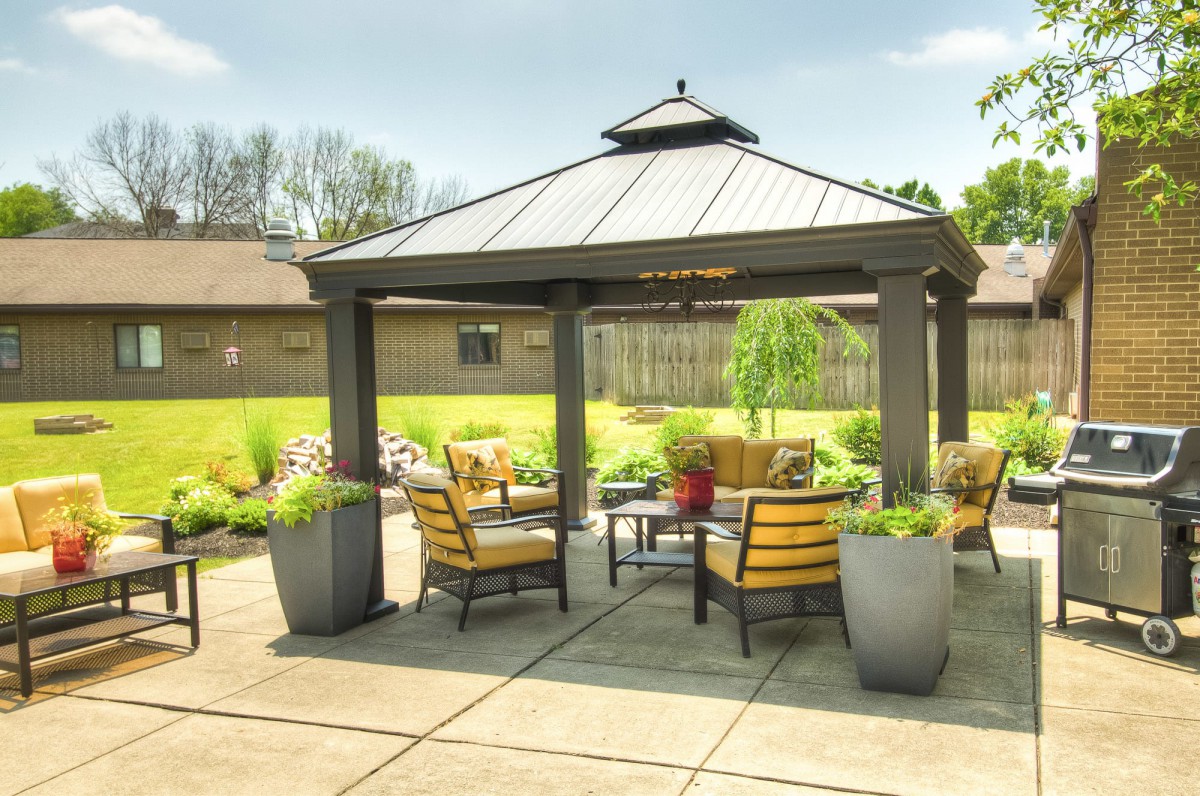 A cozy outdoor gazebo with comfortable seating and lush greenery.
