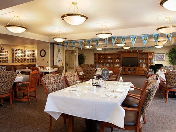 A well-lit dining area with neatly arranged tables and chairs, featuring decorative elements on the ceiling.