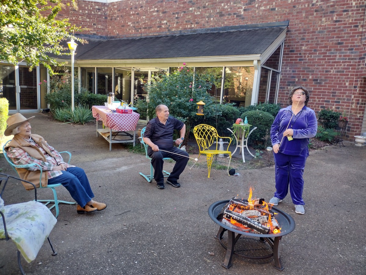 A group of people enjoying a relaxing time around a fire pit on a patio.