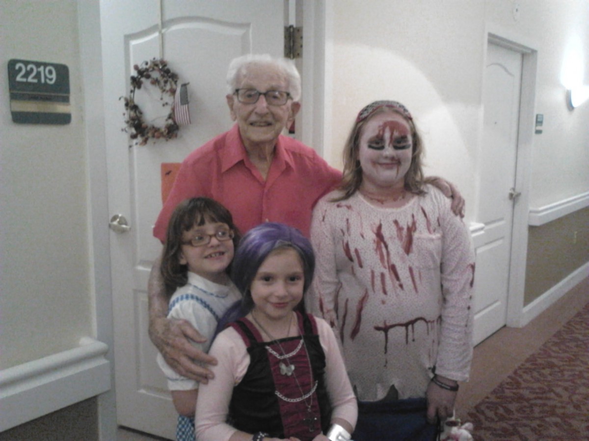 A group of children in costumes and face paint posing indoors with an elderly man.