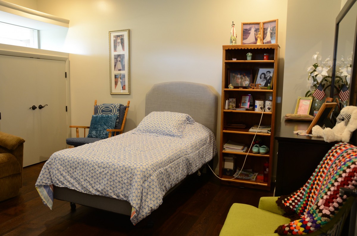 A cozy bedroom with a single bed and a bookshelf filled with framed photos and decor.