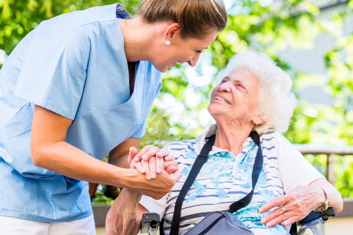 A caregiver connects warmly with an elderly woman, showcasing compassion and support in a serene outdoor setting.