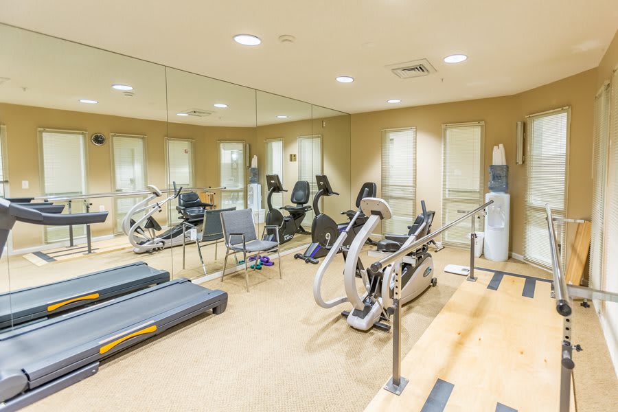 A well-equipped gym with treadmills, stationary bikes, and mirrored walls.