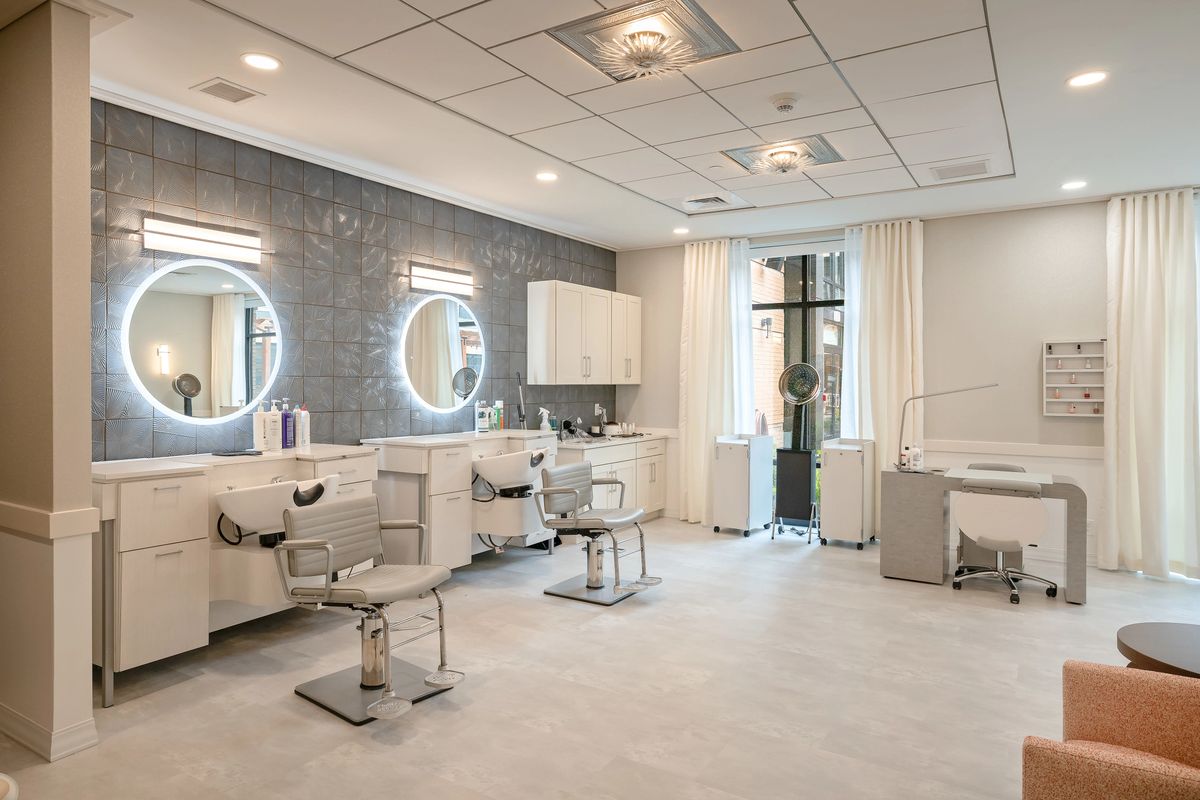 A modern, well-lit beauty salon with styling chairs and illuminated mirrors.