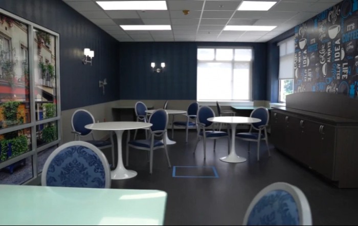 A modern dining area with blue and white decor, featuring multiple tables and chairs.