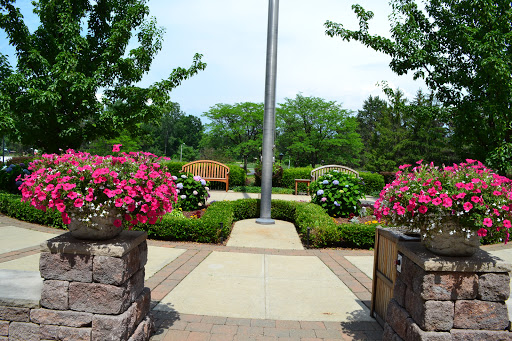 A serene park entrance adorned with vibrant flowers and inviting benches.