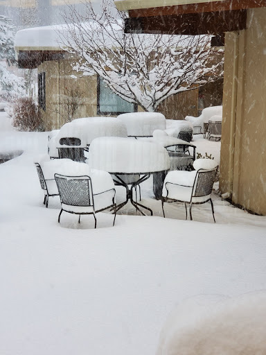 A winter scene with a table and chairs covered in a thick layer of snow.