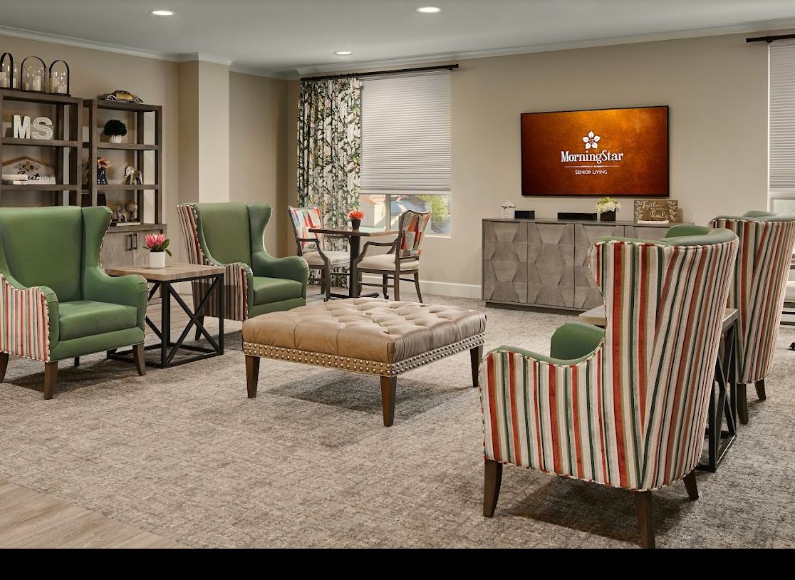 A cozy living room with various seating options and a television on the wall.