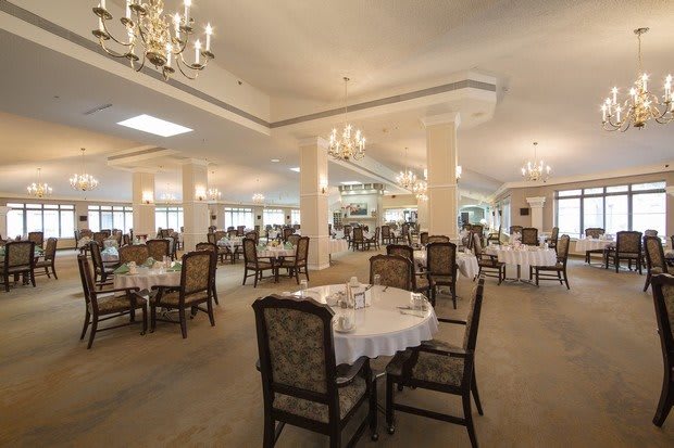 An elegant restaurant dining room with chandeliers and neatly arranged tables and chairs.