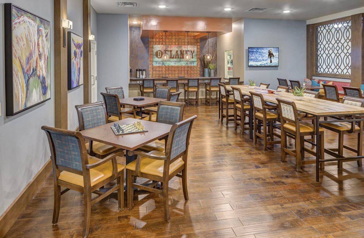 Spacious dining area with neatly arranged tables and a bar in the background.