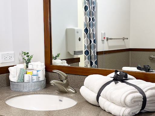 A neatly organized bathroom featuring plush white towels, essential toiletries, and a stylish mirror.