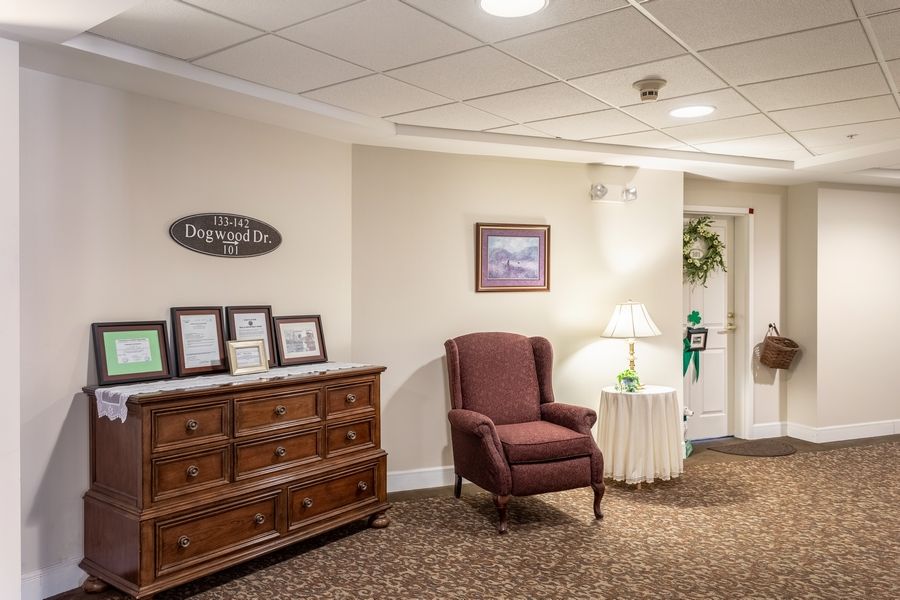 A cozy lobby area with a wooden dresser, upholstered chair, and decorative elements.