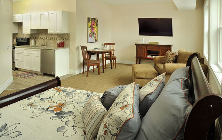A cozy living space featuring a comfortable sofa, a wall-mounted television, a small dining area, and a kitchenette.