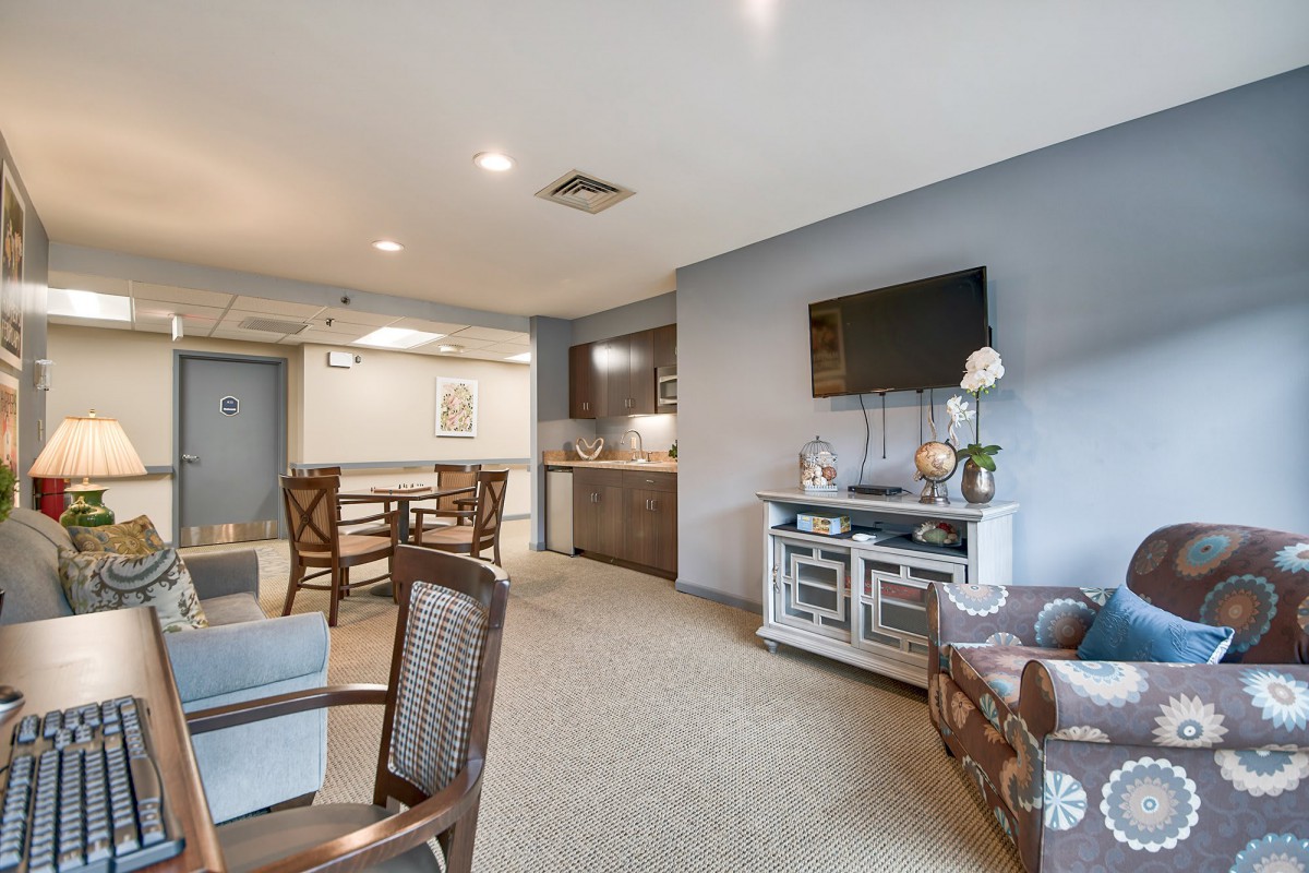 A modern open-concept living and kitchen area featuring stylish furniture and a mounted television.