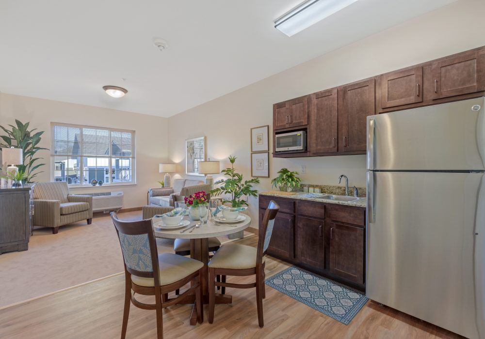 A modern apartment interior featuring a kitchen and dining area with stainless steel appliances and stylish furniture.