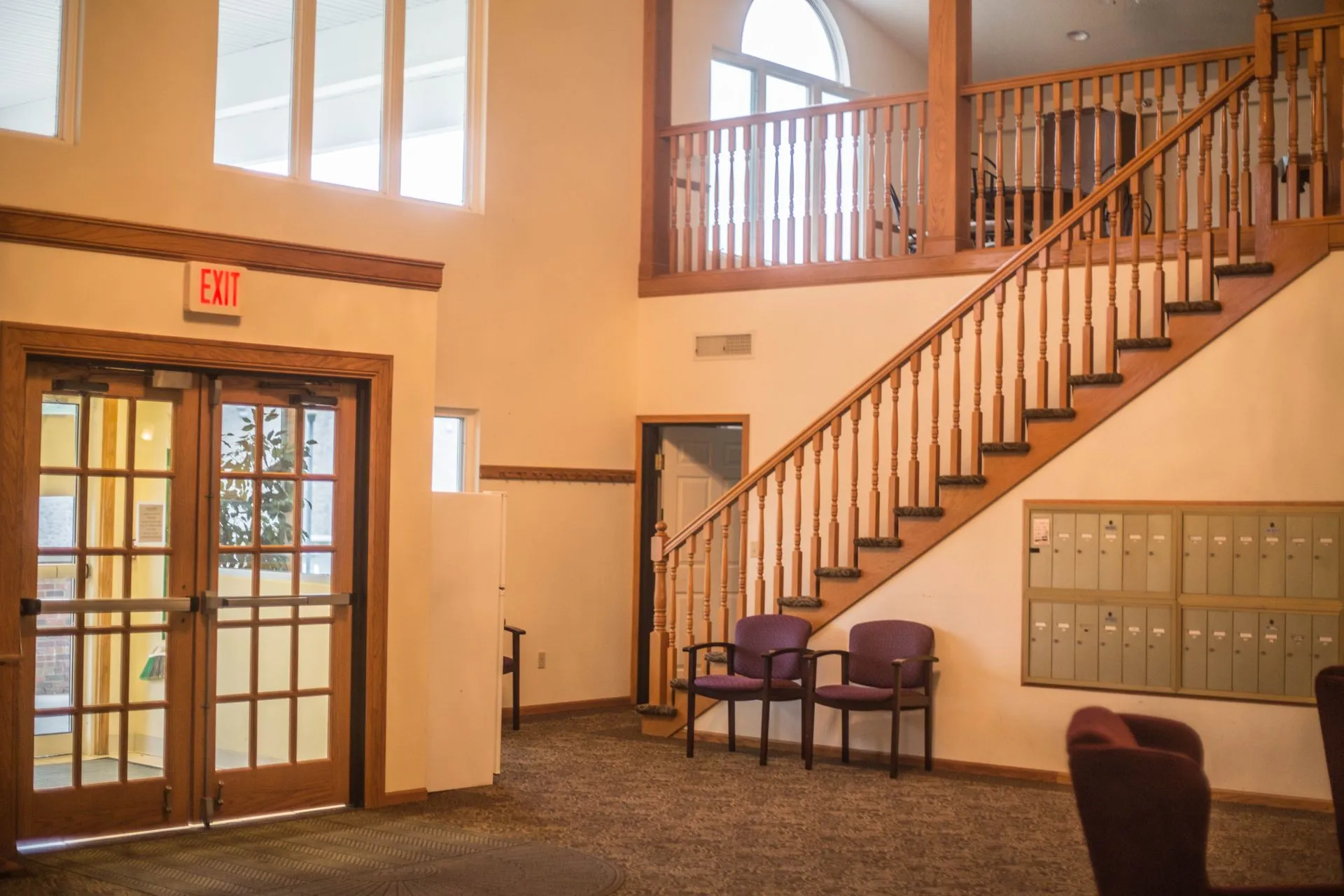 A cozy lobby interior with a staircase and a waiting area with chairs.