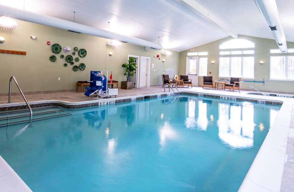 An inviting indoor swimming pool area with seating and wall decorations.
