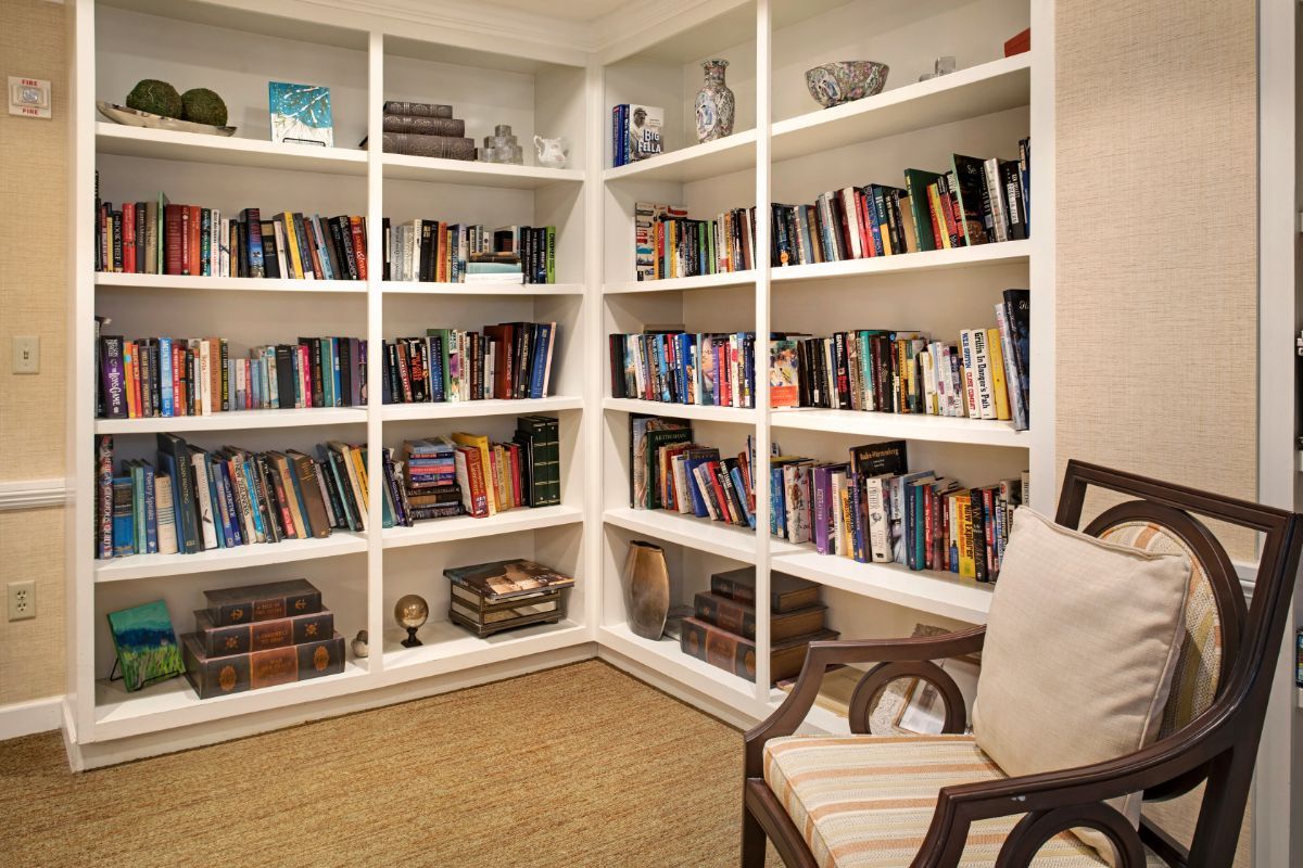 A cozy home library with white bookshelves filled with a variety of books.