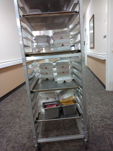 A food cart filled with containers ready for service in a dining area.