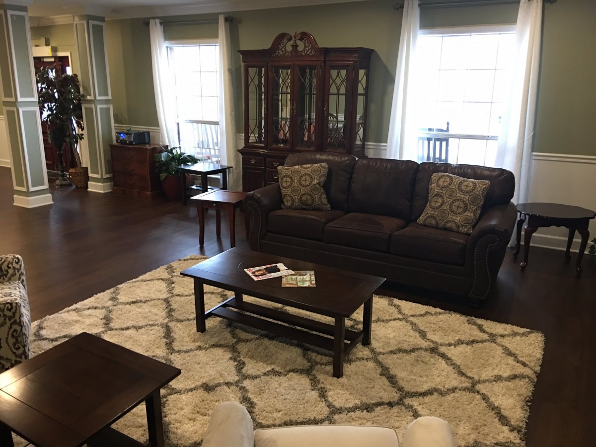A cozy living room with a dark sofa, coffee table, and ornate wooden cabinet.