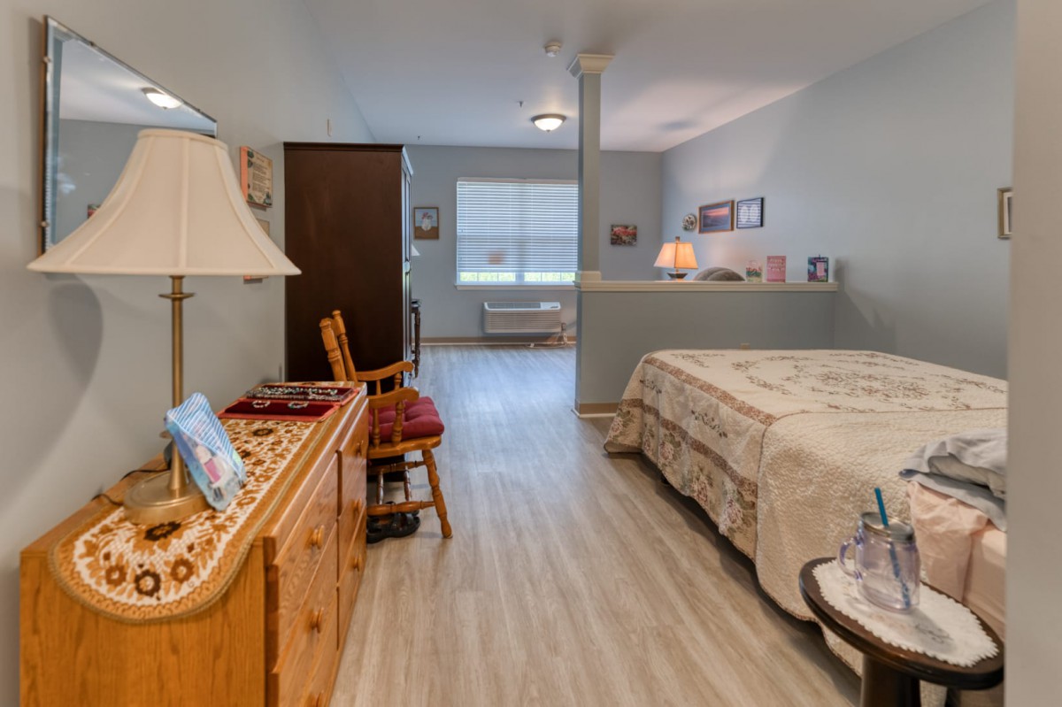 A cozy bedroom with a neatly made bed and classic wooden furniture.