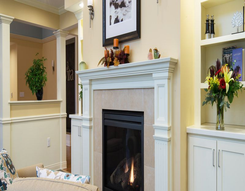 A cozy living room featuring a modern fireplace with elegant mantel decor.
