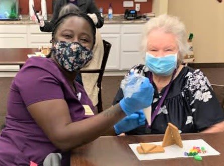 A healthcare worker administering a vaccine to an elderly patient, both wearing masks for safety.