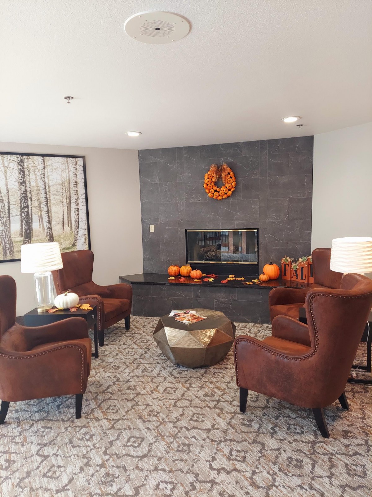 A cozy living room with autumn-themed decor and a fireplace.