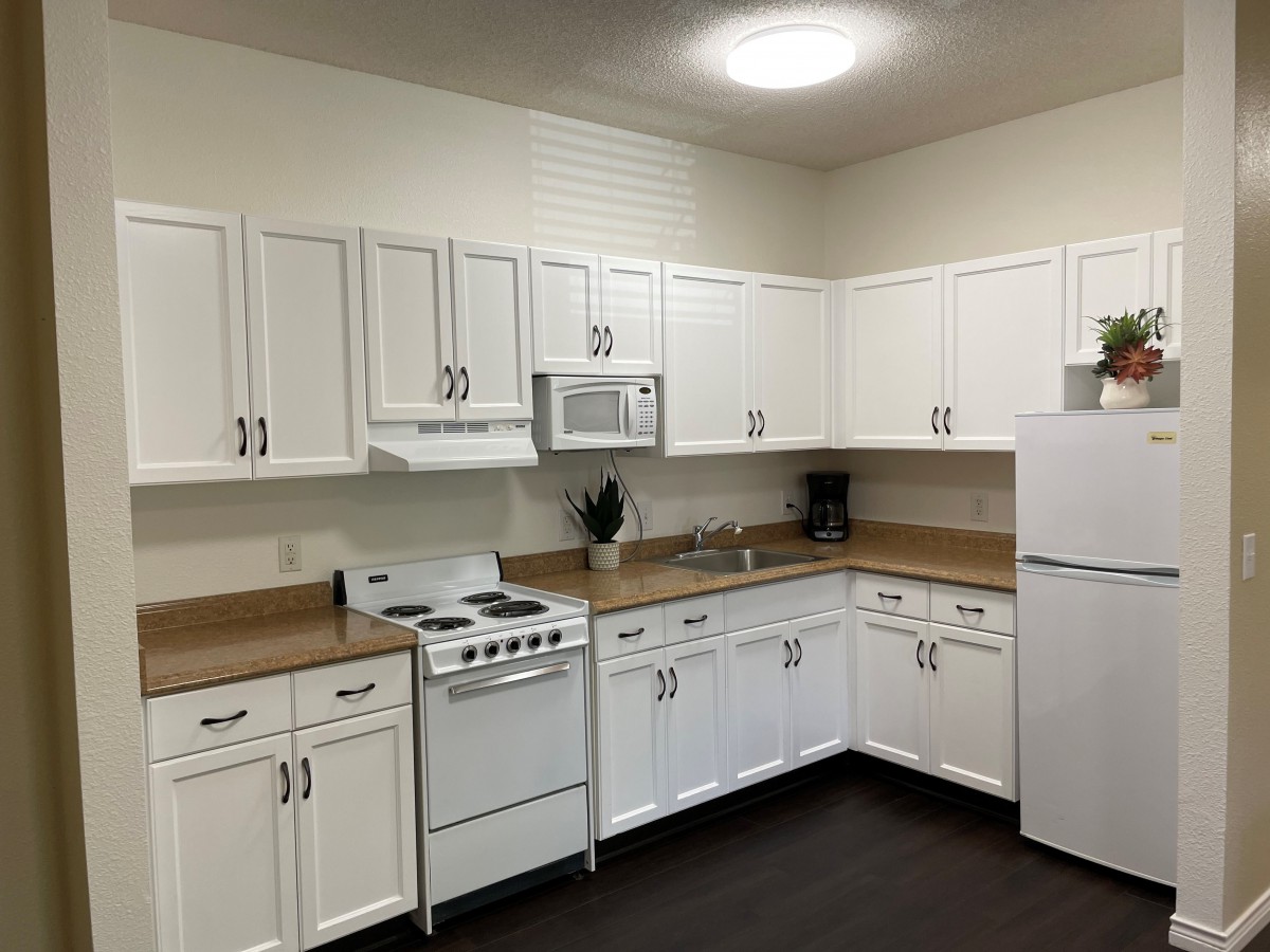 A modern kitchen with white cabinets and appliances including a stove, microwave, and refrigerator.