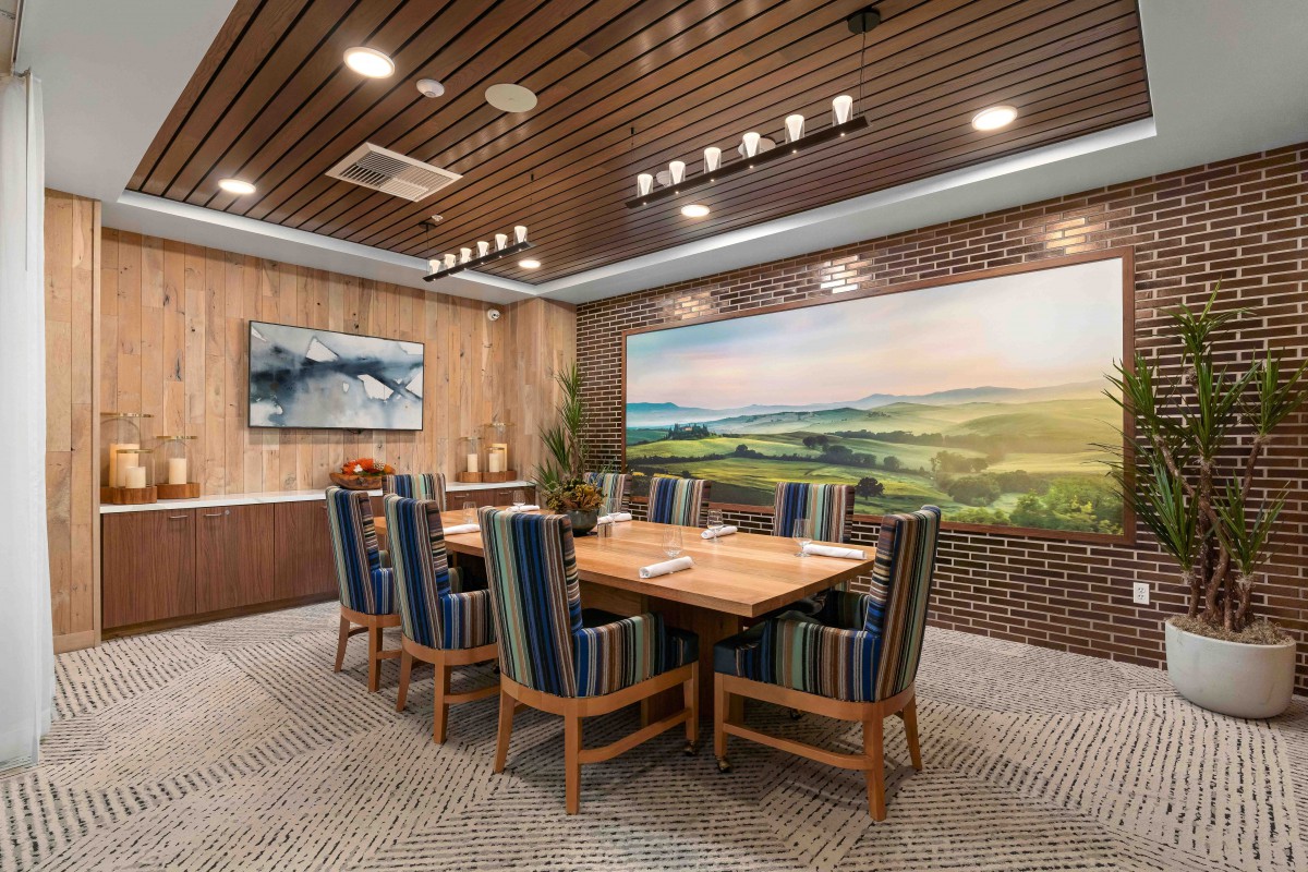 A modern conference room featuring a large wooden table, striped chairs, and decorative wall art.