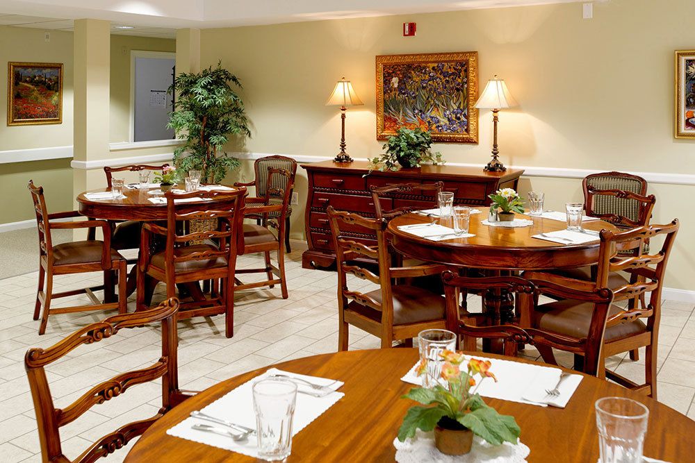 A cozy and elegantly furnished dining area with wooden tables and chairs, decorated with plants and soft lighting.
