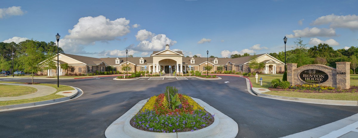 A scenic view of a building's entrance with a landscaped garden and clear blue sky.