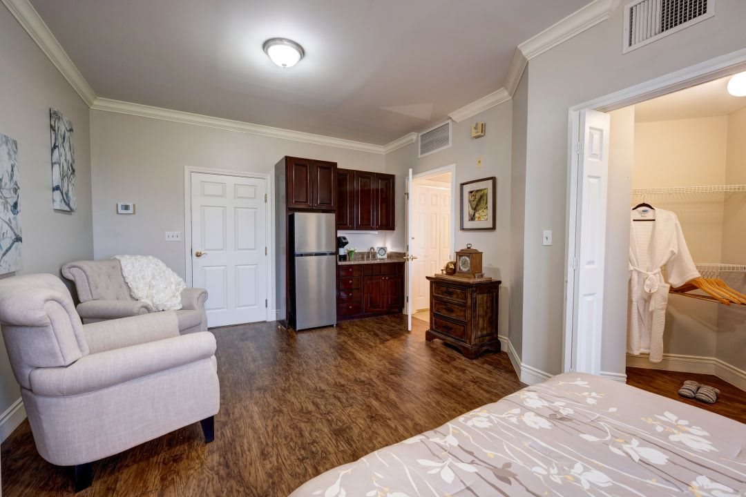 A cozy studio apartment with a living area, kitchenette, and hardwood flooring.