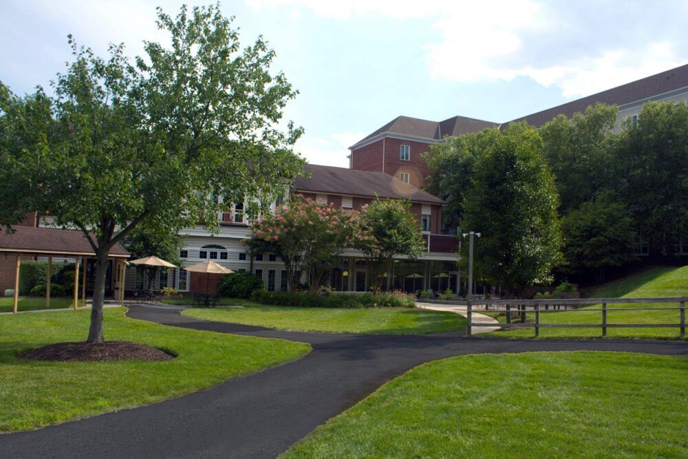 A scenic view of a building surrounded by a landscaped garden with trees and a walkway.