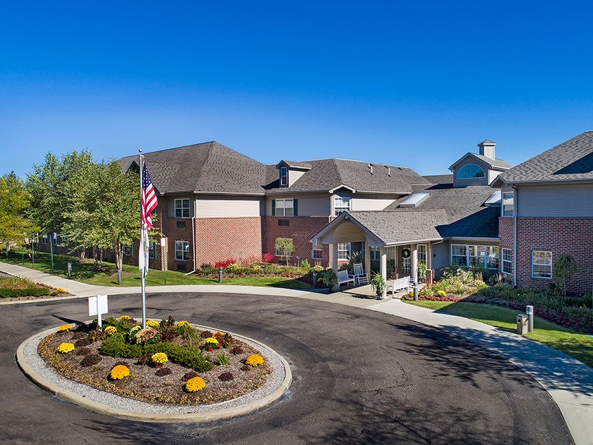A residential building with well-maintained landscaping and an American flag on a sunny day.