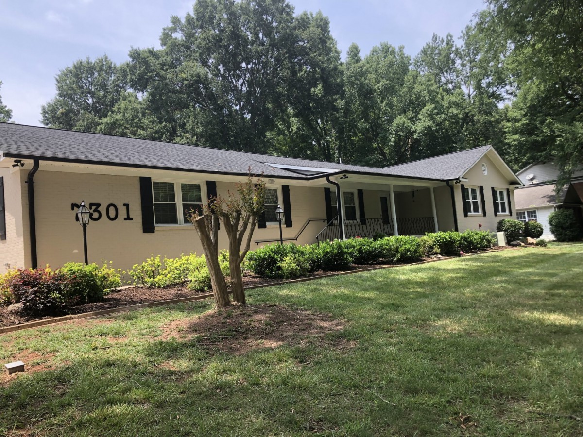 A single-story suburban house with a well-maintained front yard and surrounding trees.