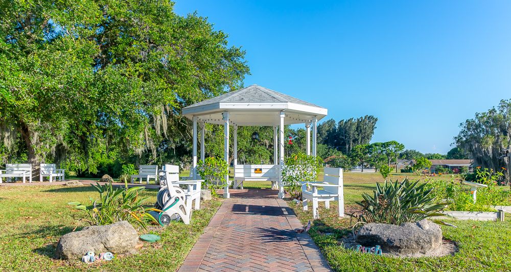 A scenic view of a gazebo surrounded by benches and lush greenery in a park.