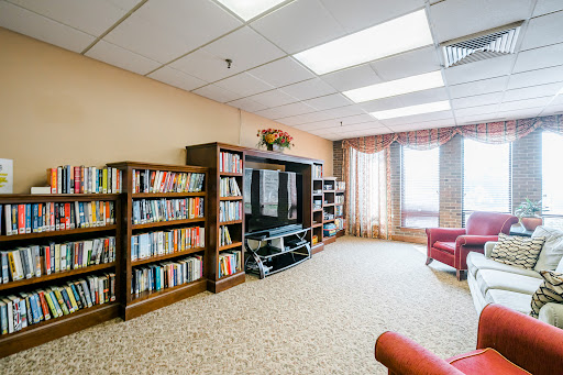 A cozy living room setup with bookshelves filled with books, a TV unit, and comfortable seating by the window.