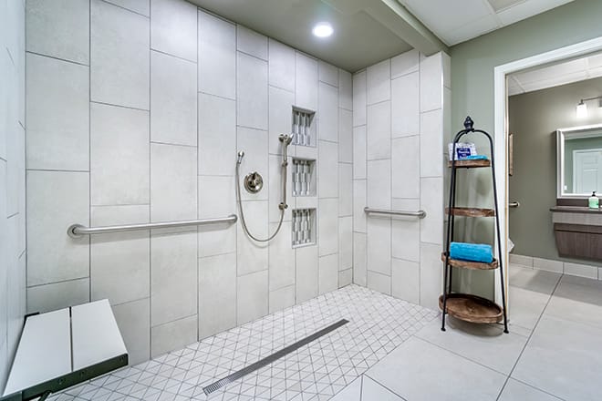 A modern walk-in shower with tiled walls and floor, equipped with grab bars and a handheld showerhead.